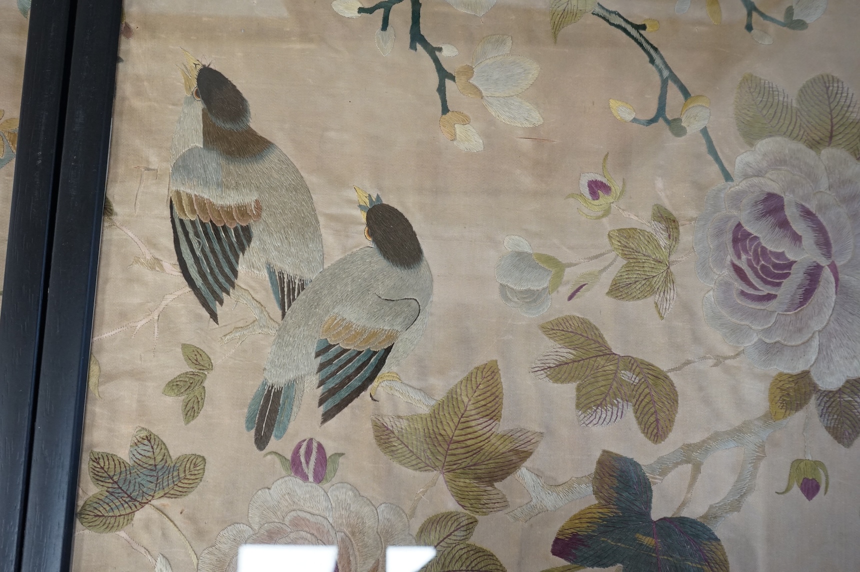 A pair of framed 19th century Chinese silk embroideries of exotic birds amongst entwined flowering branches, embroidered on a beige silk back ground, possibly cut from a larger embroidery. 47cm x 57cm., Condition - one f